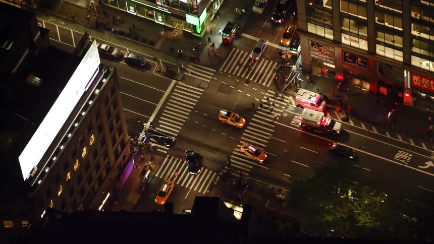 Ambulances sit with their lights flashing on a city street as traffic passes by