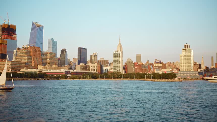 A coastal city with boats and a yacht with buildings and skyscrapers in the background
