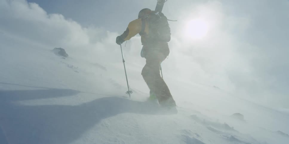 Skier trekking uphill in the snow during a blizzard