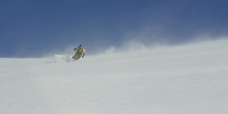 A skier makes turns on a windblown slope