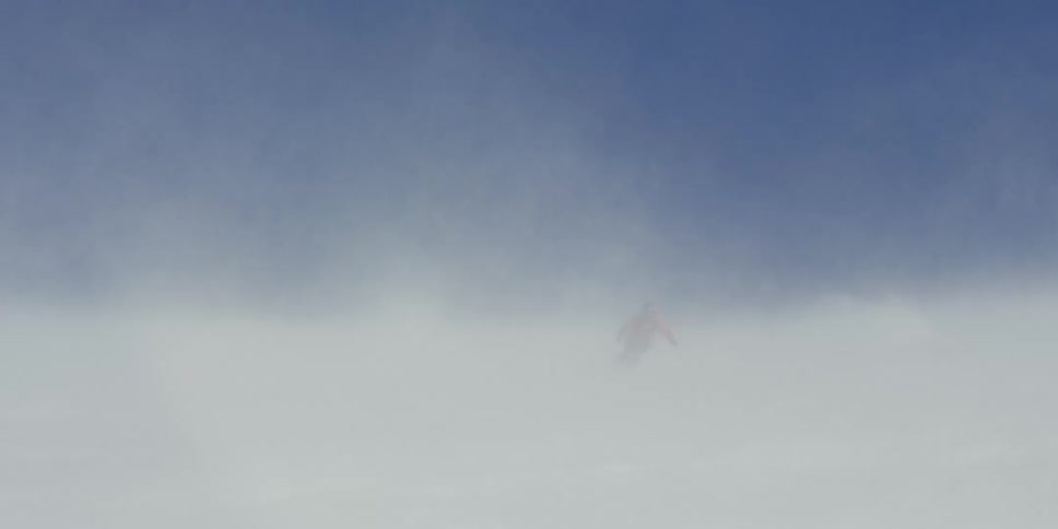 A skier appears out of windblown snow
