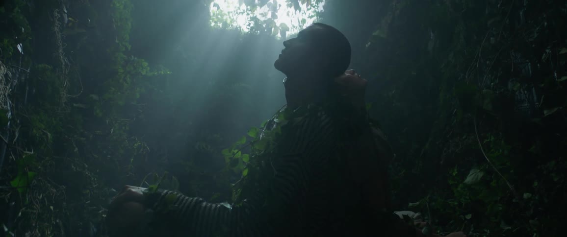 A man and woman lean against each other in the dark green filled room