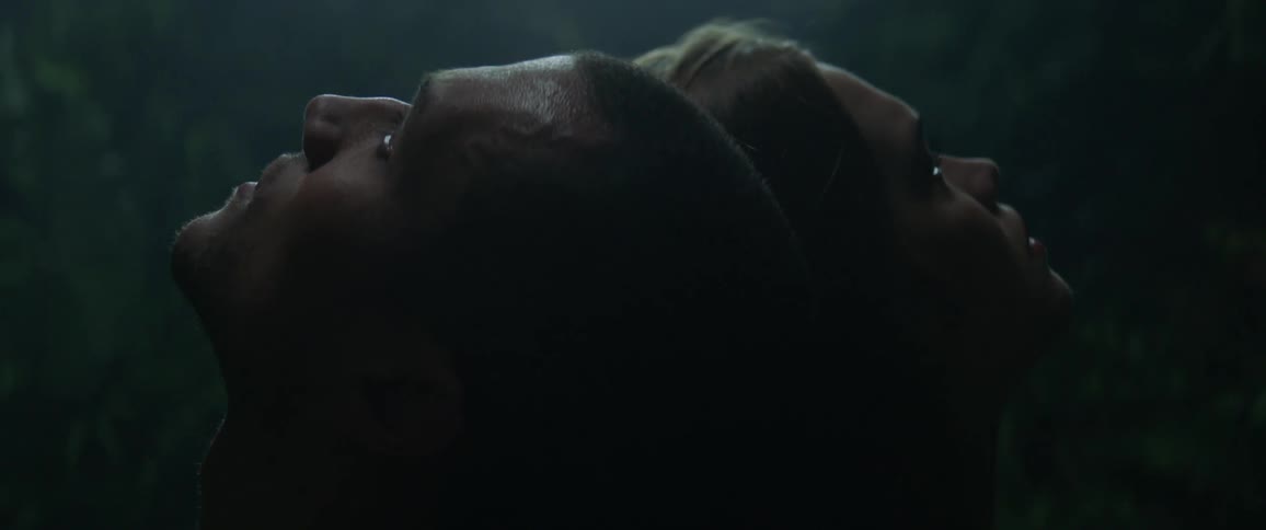 A man and woman sit back to back while looking upward