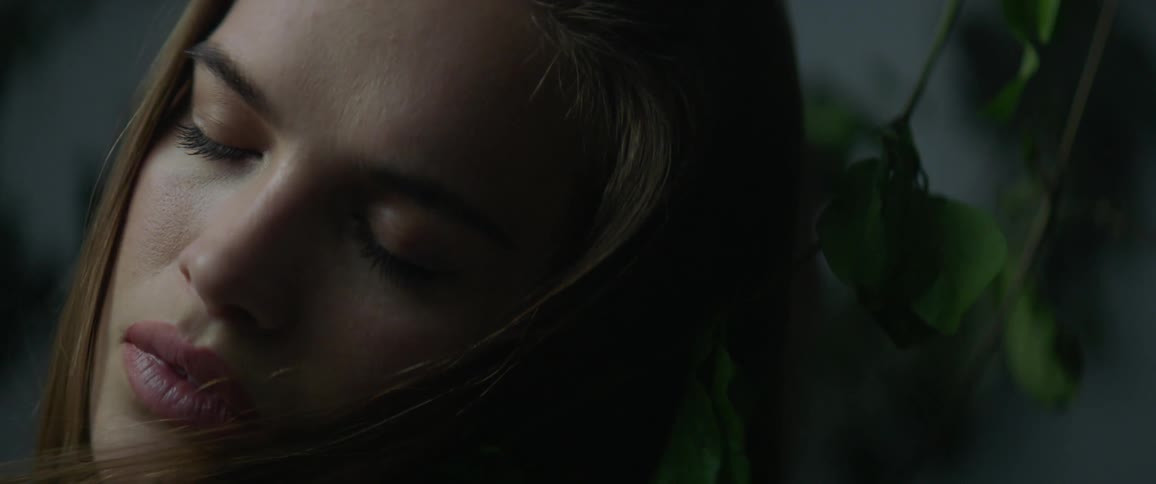 A woman is sleeping as vines move around her