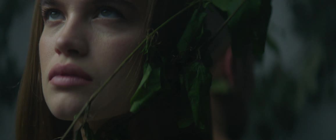 A vine grows and slides against a woman's face