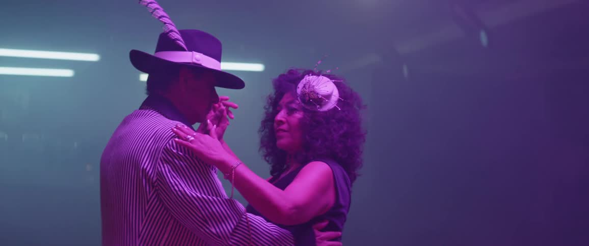Man and woman dance illuminated by bluish light