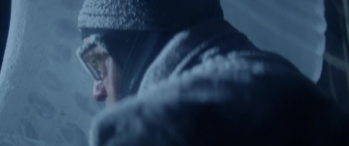 Man covered in front scrapes ice away from a large circular object
