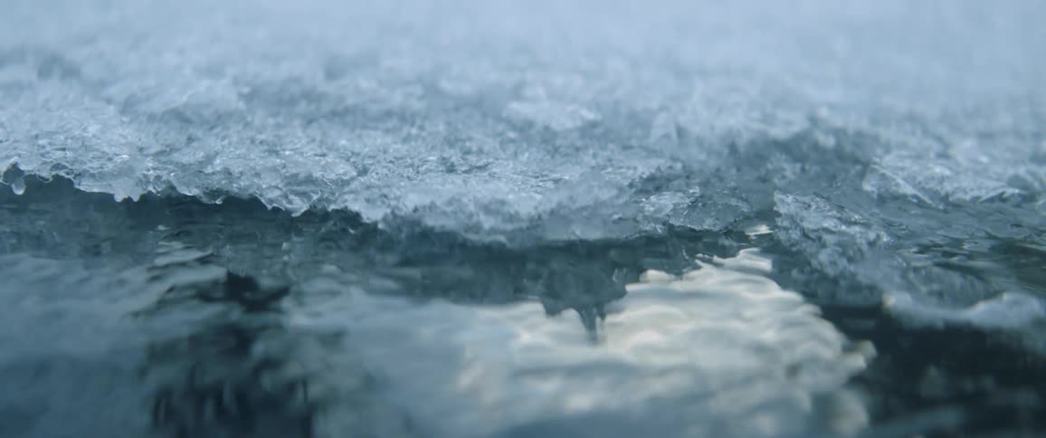 Ice is floating on top of a trickling stream of water during the day