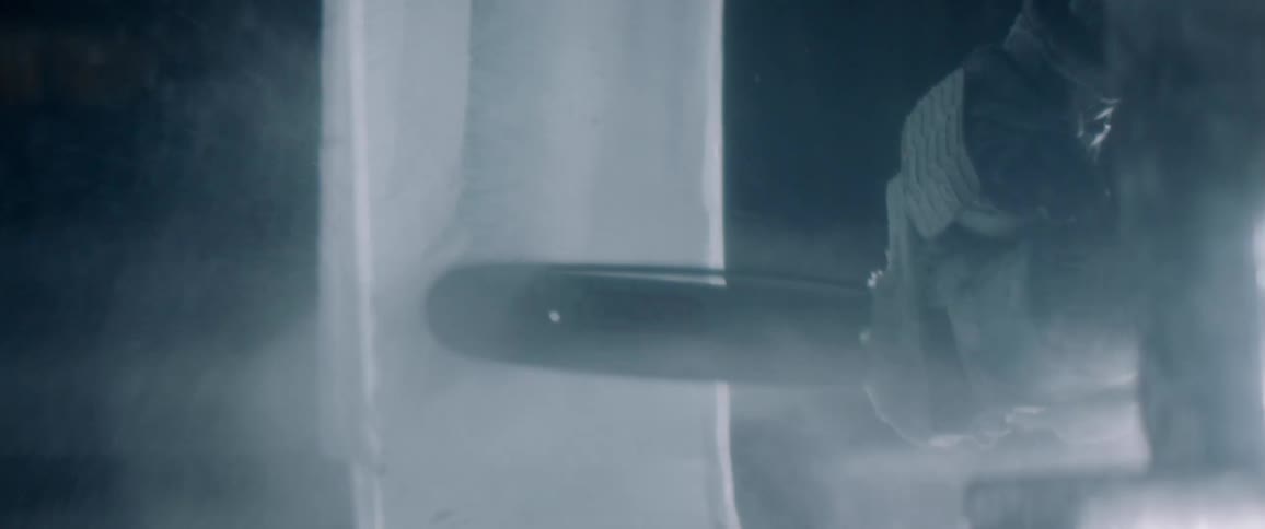 Person saws through a large block of ice with a chainsaw