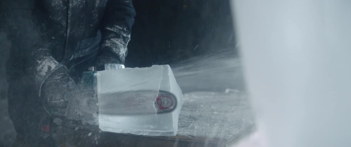 Person saws through a large block of ice with a chainsaw