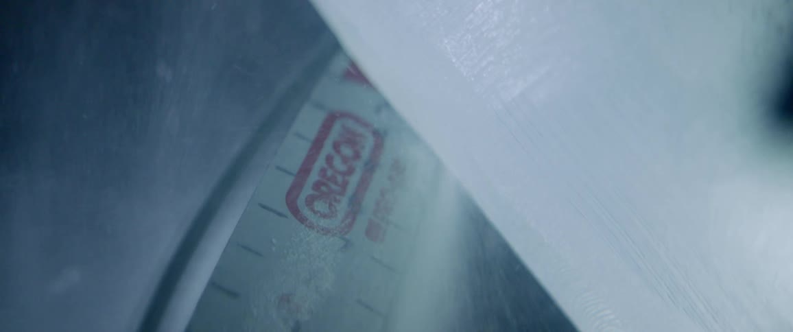 A chainsaw is being used to carve ice outside in daylight