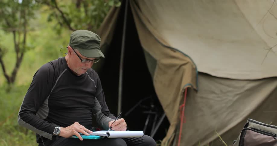 A man in a black shirt writes on a notepad