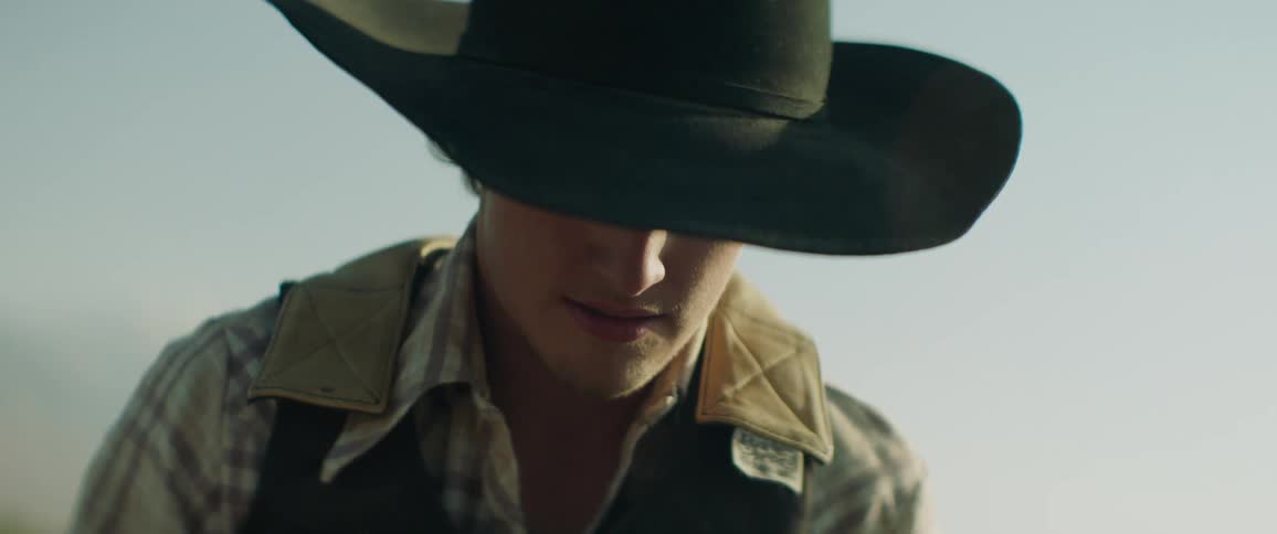 A rodeo cowboy is concentrating on something during the day
