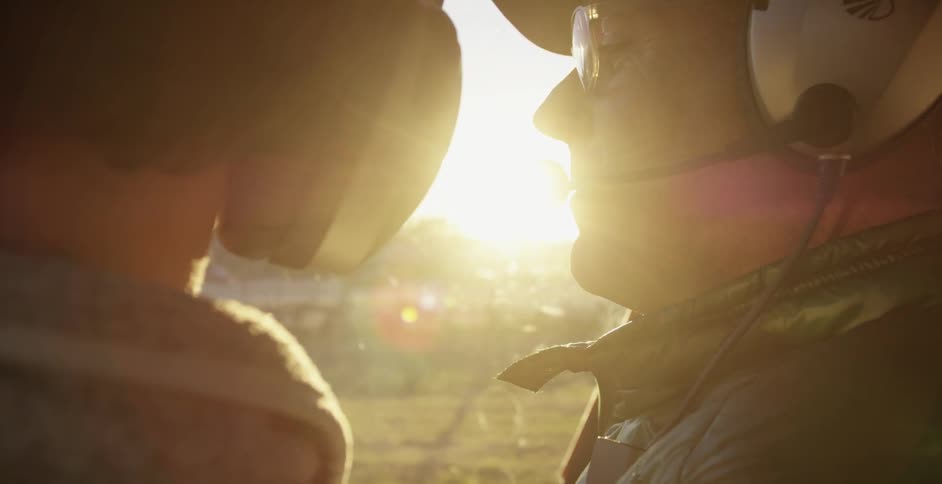 Two men wearing headsets look out a window
