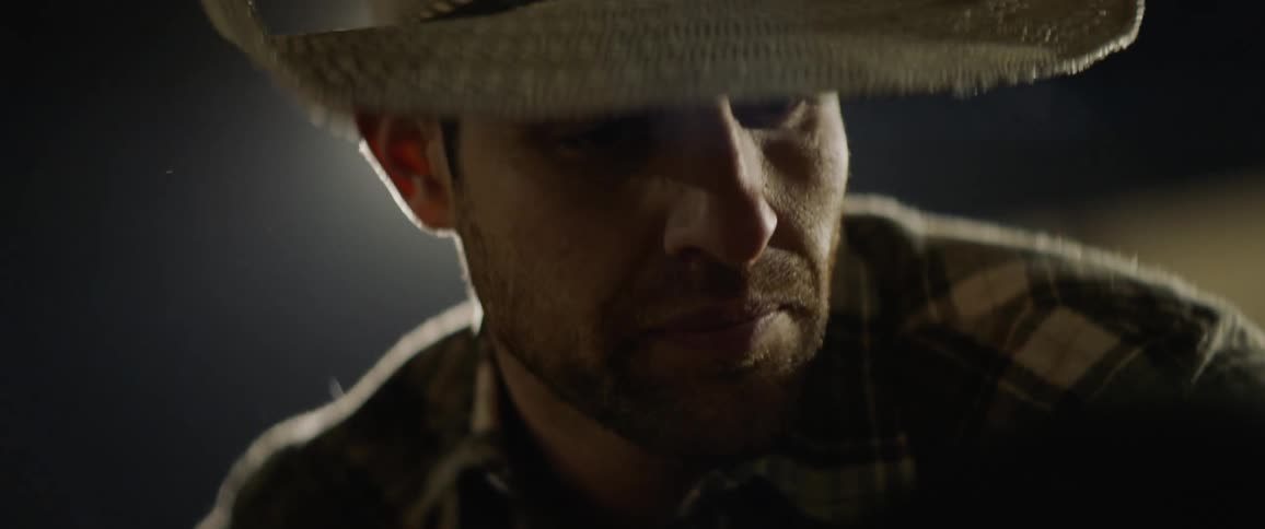 A cowboy talks to a rider in a rodeo chute