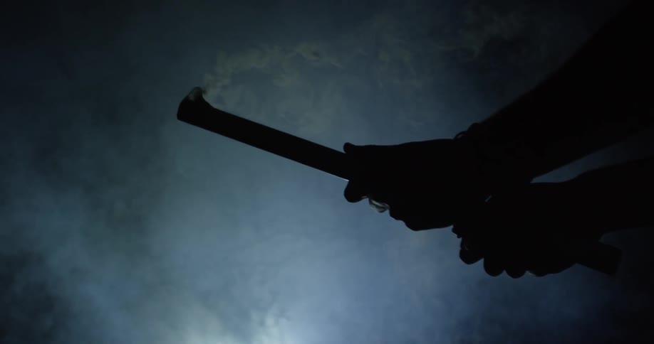 A man is shooting off a firework in a dark area