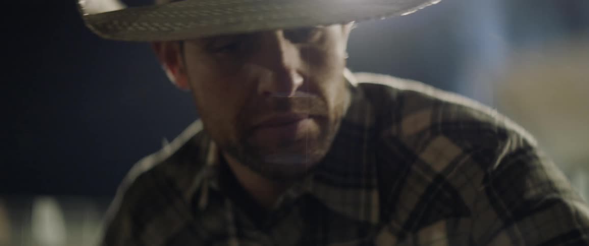 A man wearing a cowboy hat shouts at someone