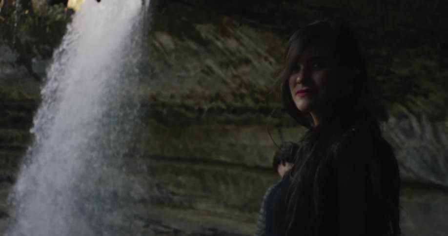 A woman is watching at the foot of a waterfall