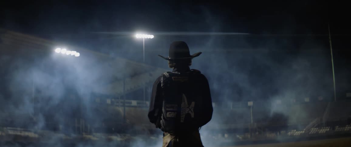 A cowboy stands in a misty arena