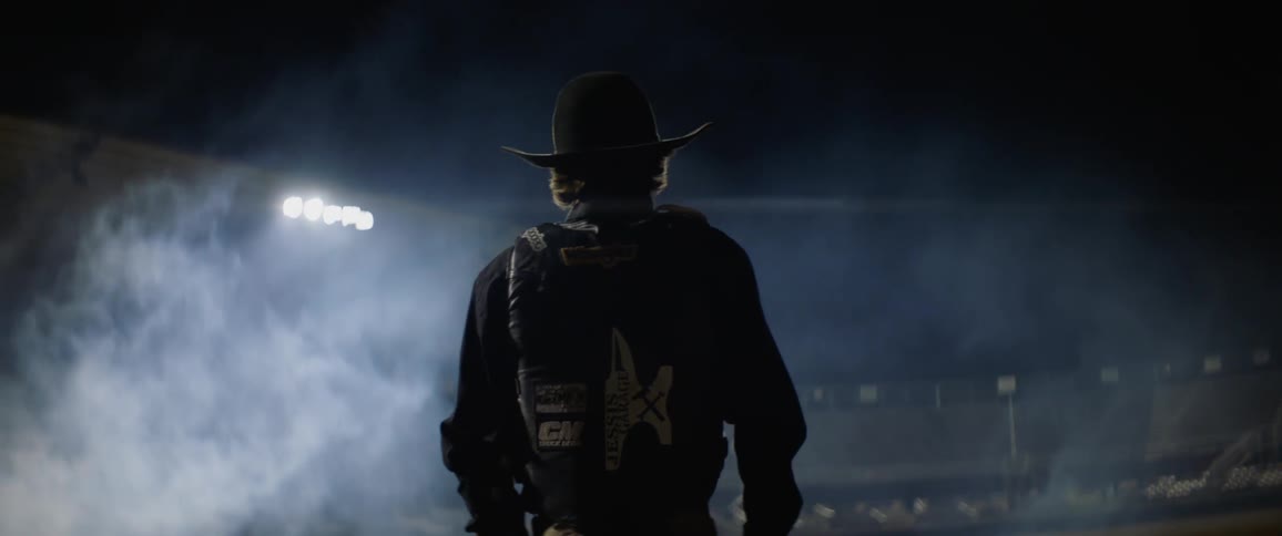 Cowboy stands and looks into rodeo arena