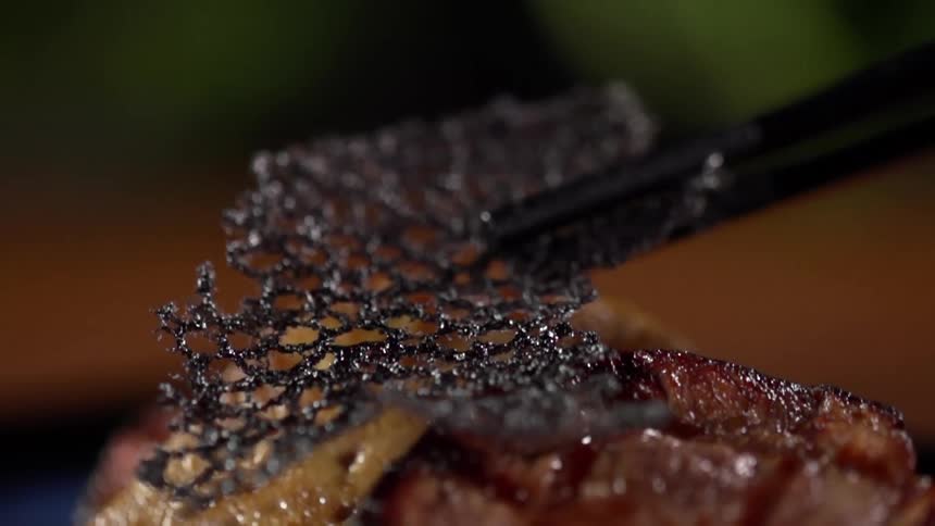 Caramel mesh placed with tongs over roasted meat