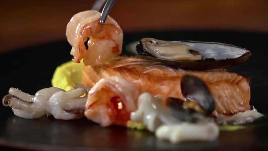 A shrimp is set down on a plate with seafood