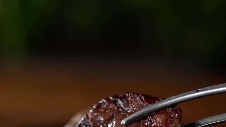 A small round piece of grilled steak is carefully placed on a plate