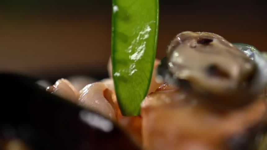 A green bean is lowered into a plate of food