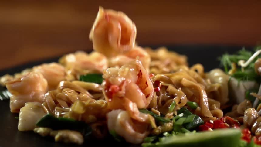 A piece of shrimp drops onto a plate loaded with food