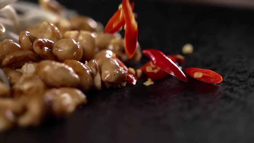 Diced red pepper falls onto a table next to food