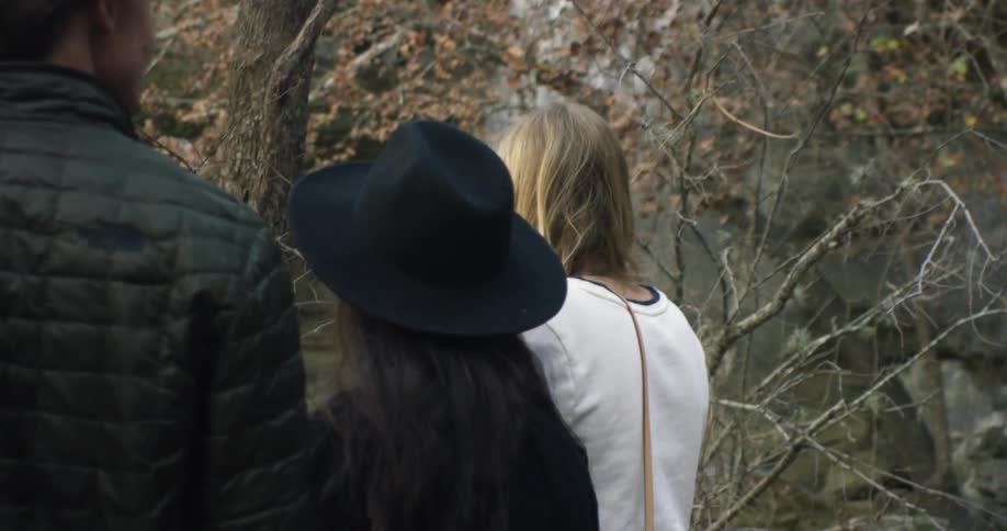 Three people are standing at the foot of a waterfall