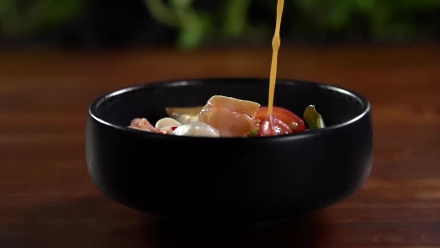 Sauce is being poured on the bowl of food