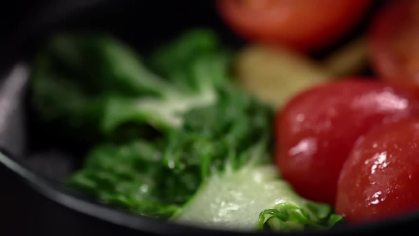 Cooked shrimp is dropped on a bowl of vegetables