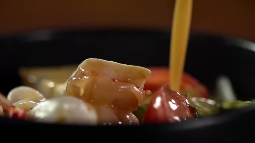 An oil based dressing poured over a vegetable salad in a bowl