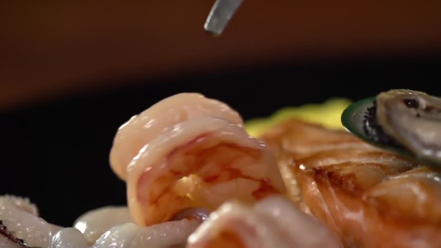 Shrimp being placed on a bed of seafood