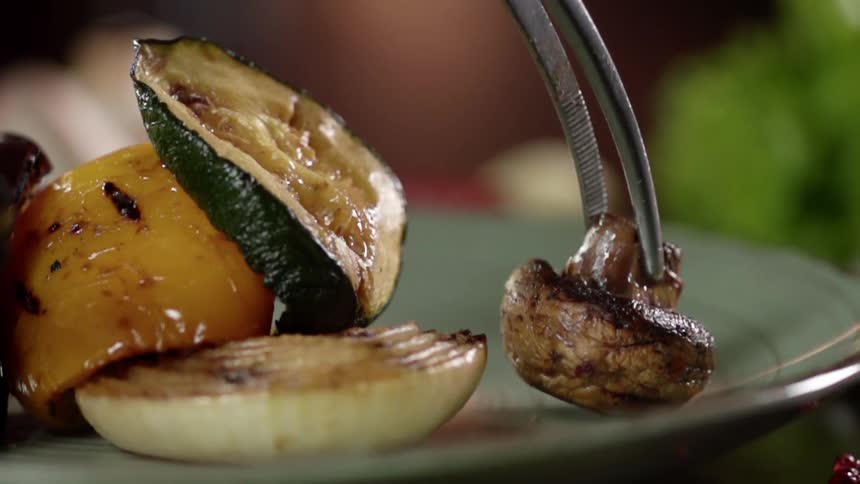 Grilled mushroom being served in a dish near grilled vegetables