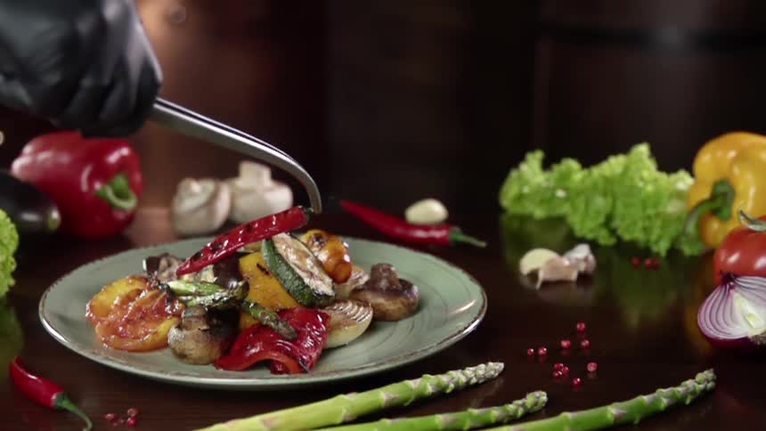 A person puts a pepper on top of a meal