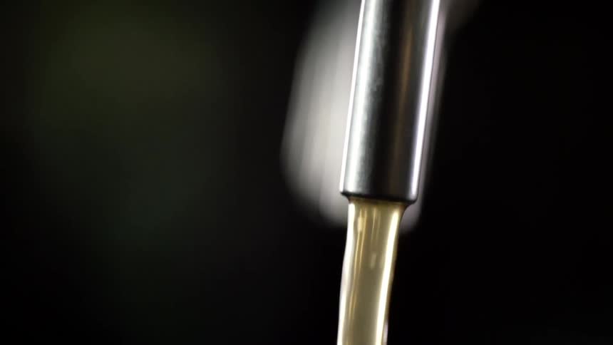 Liquid pouring out of a narrow metal spout