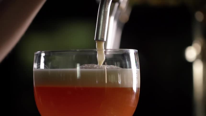 Beer is filling the glass from the tap