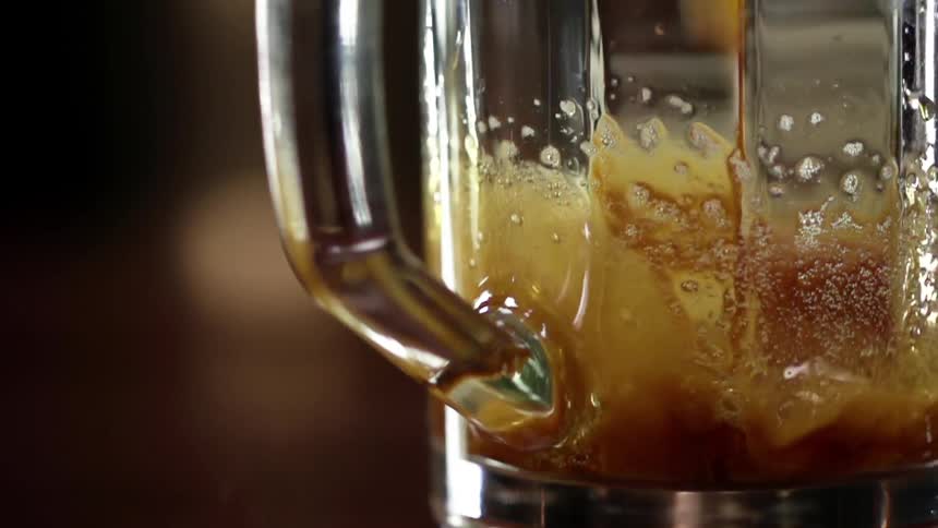 A brown liquid pouring into a glass mug