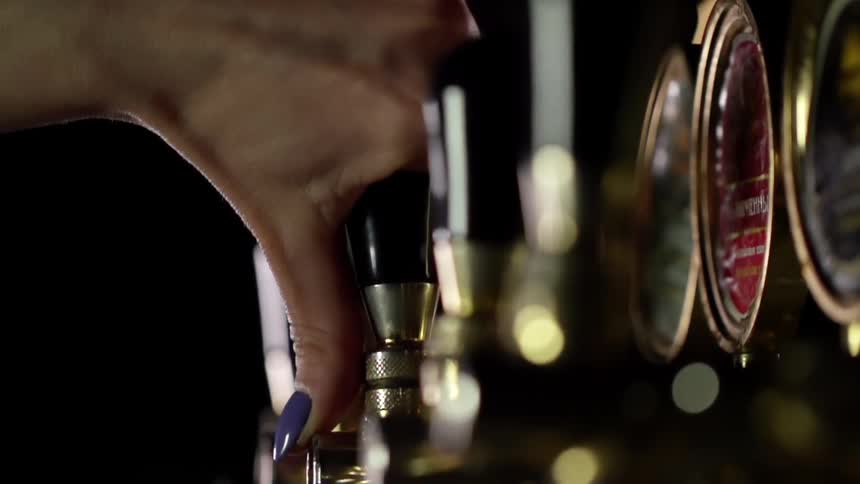 A white woman works a beer tap
