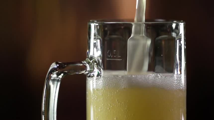 Pouring beer into a glass and rising to a head