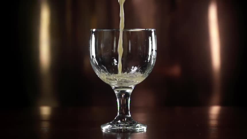 Pouring beer in a goblet at bar counter in slow motion