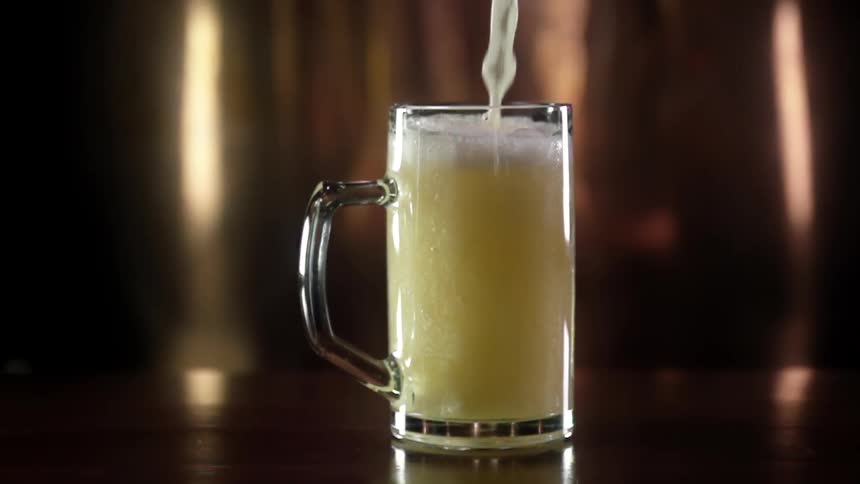 Beer pours into a glass mug