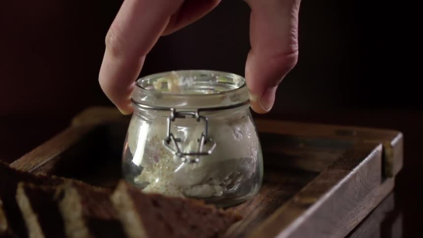 A man sets a jar down on a wooden tray