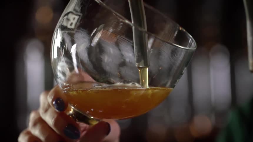A white woman fills a glass with beer from a tap