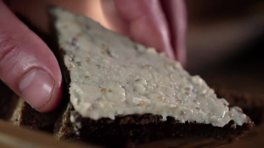 A white person puts a piece of bread covered in spread on top of another piece of bread