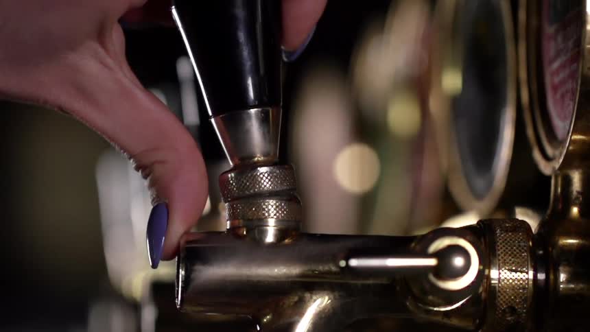 A white woman works a beer tap with her hand