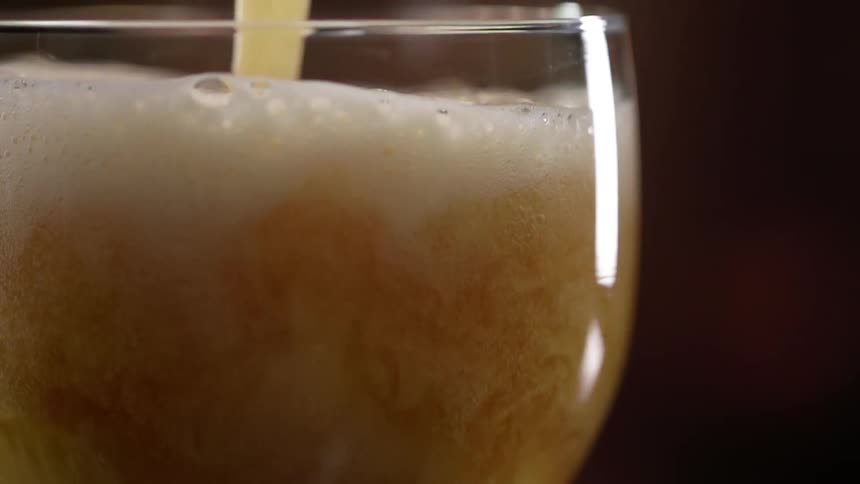 A glass fills with foamy beer