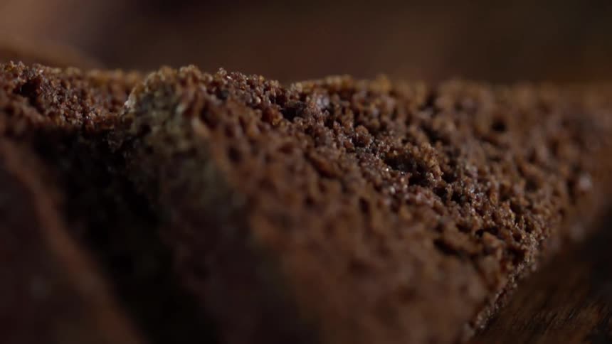 Brown textured grain food sits on dark brown surface backed by brown background